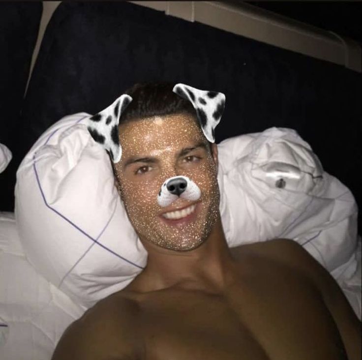 a man laying in bed with a dalmatian dog on his head and nose