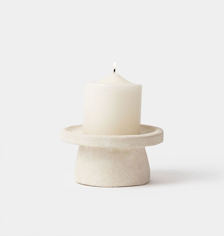 a white candle sitting on top of a stone stand with one candle in it's center