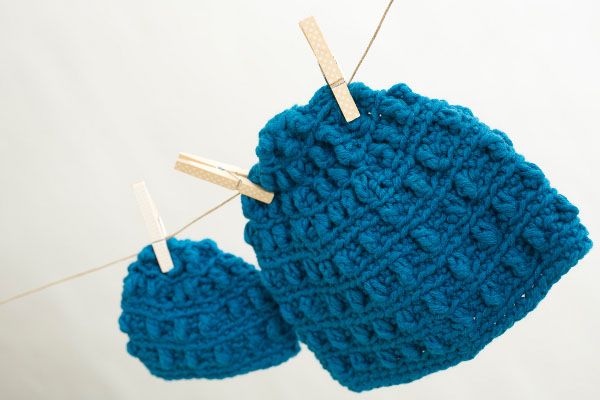 blue knitted mitts hanging from clothes pins on a white background with pegs