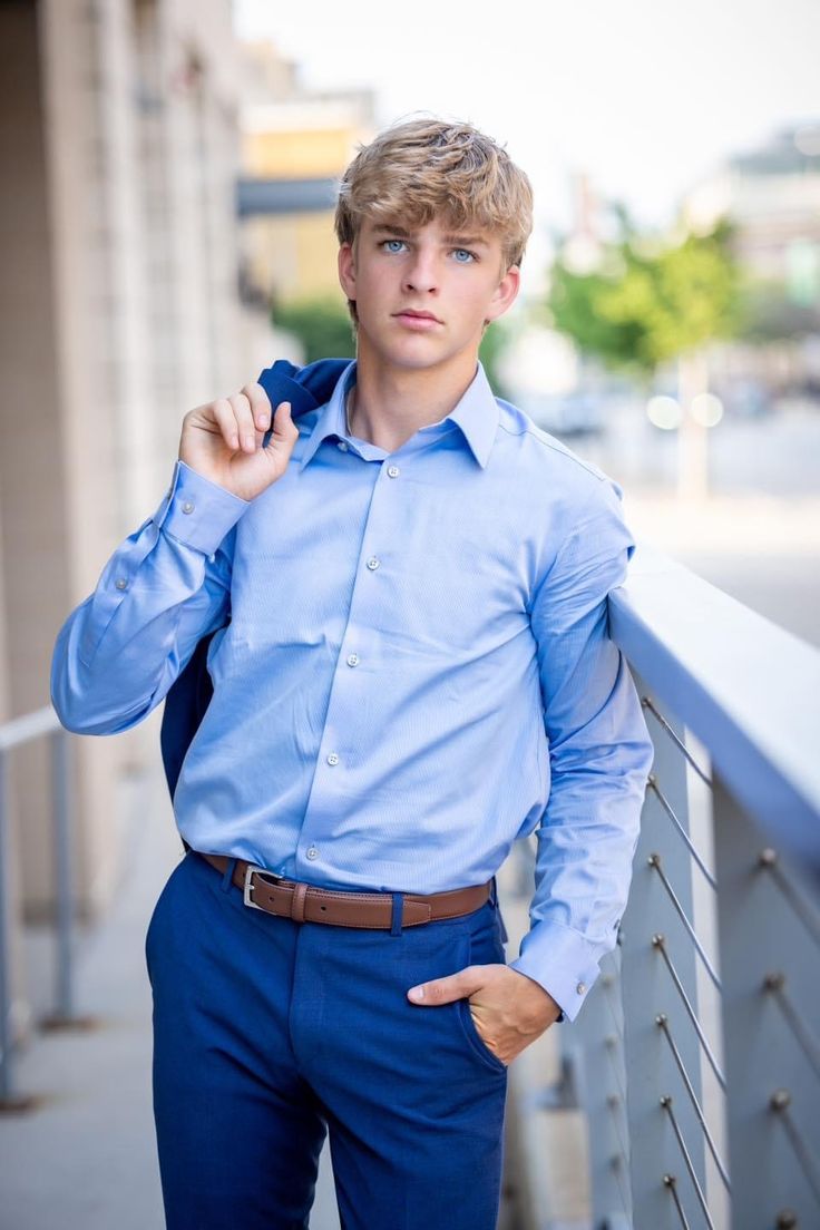 a young man is posing for a photo while leaning against a railing with his hands in his pockets