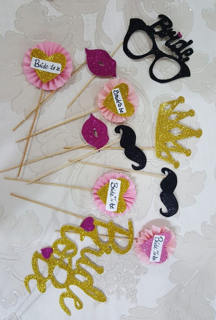 some pink and gold cake toppers are sitting on a white tablecloth with lace