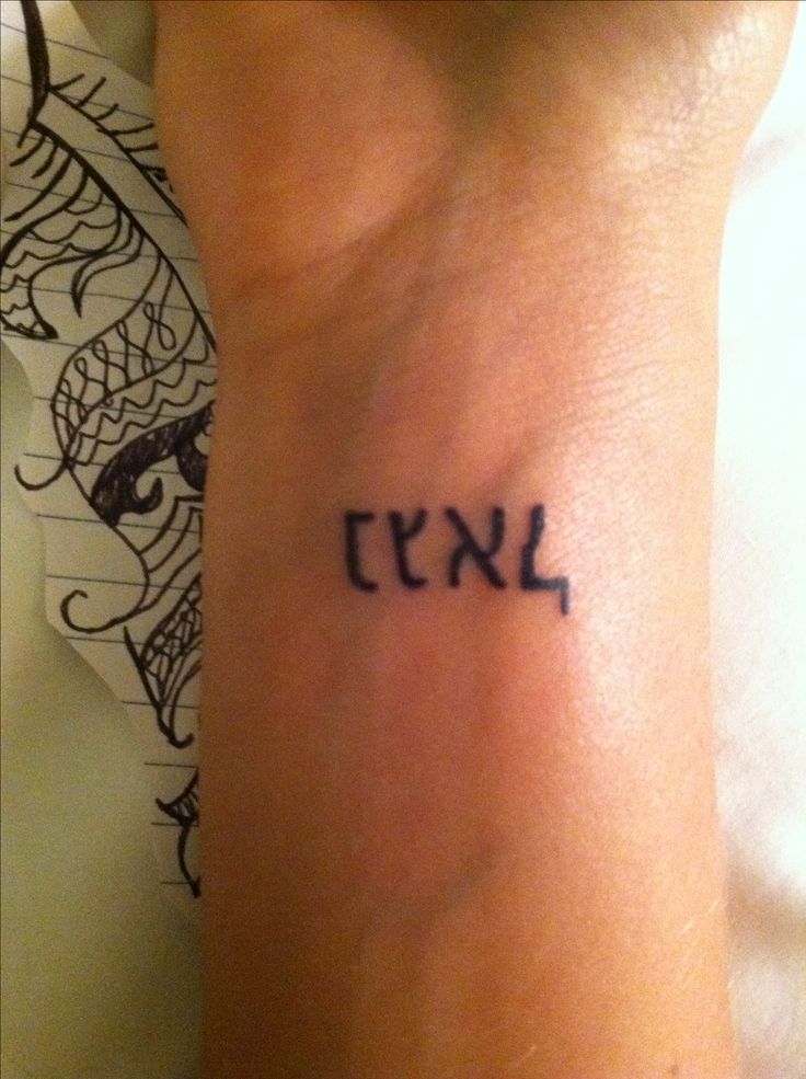 a small wrist tattoo with the word in hebrew