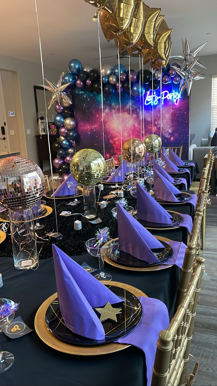 a long table set with purple and gold plates, silverware, and star decorations