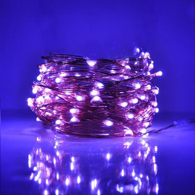 purple fairy lights are lit up in the dark with reflections on the floor and blue background