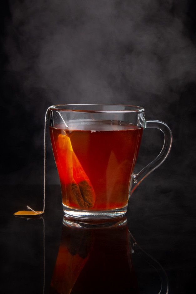 a glass cup filled with tea and orange peels on top of a black table