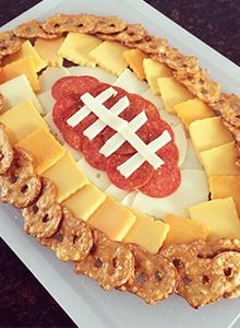 a football shaped cheese platter with pretzels and crackers