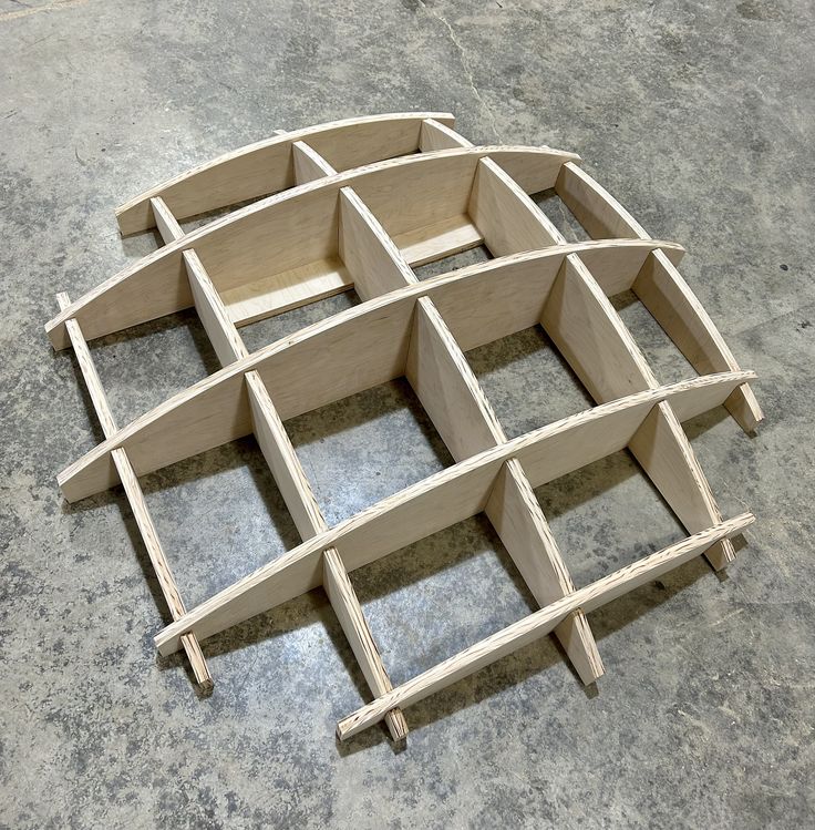 a wooden structure sitting on top of a cement floor next to a wall with holes in it