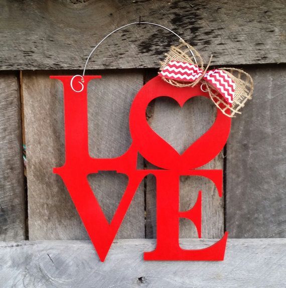 a red love sign hanging on the side of a wooden wall with a bow and checkered ribbon