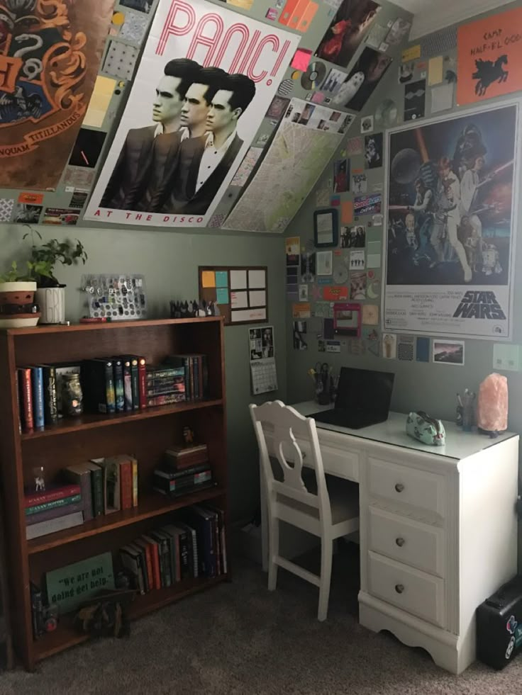 a desk and chair in a room with posters on the wall above it's head