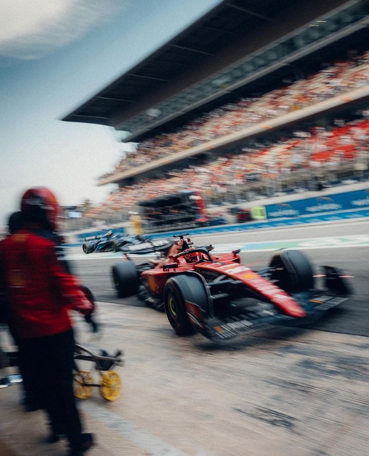 two racing cars driving around a track in front of a large group of people watching