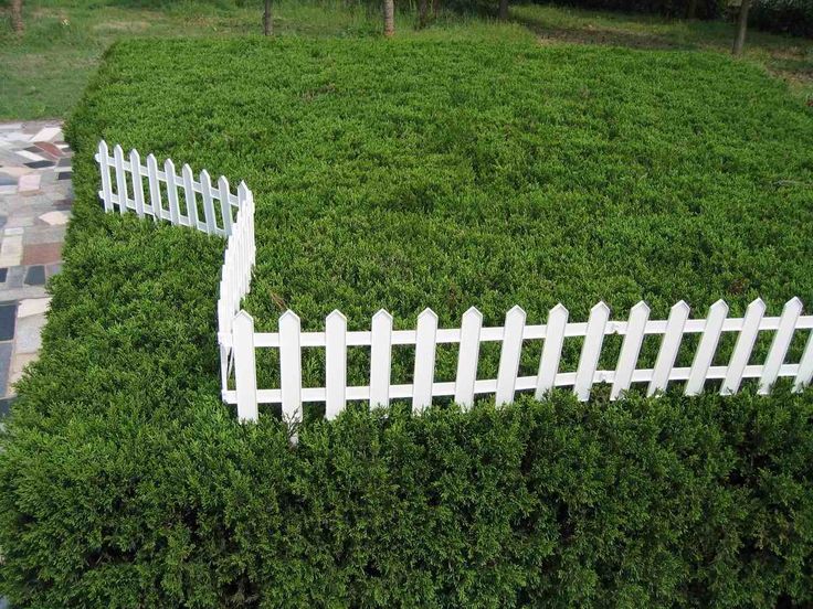 an aerial view of a white picket fence in the middle of a green lawn area