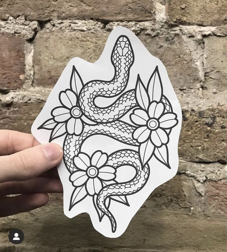 a hand holding up a sticker with an image of a snake and flowers on it