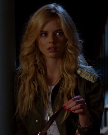 a woman with long blonde hair holding a knife in her hand and looking at the camera