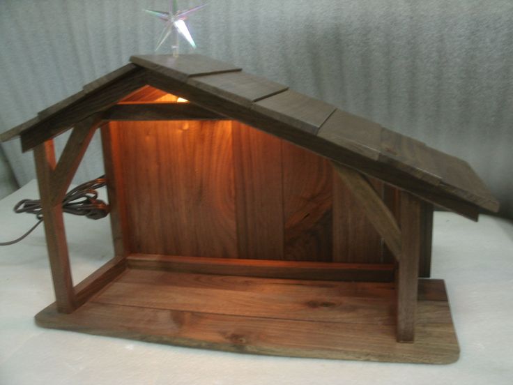 a small wooden nativity scene with a star on top and a light in the middle