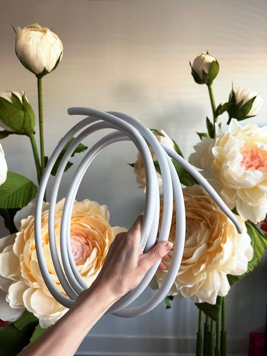 a hand is holding an object in front of some white and yellow flowers on a table