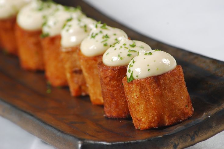 small appetizers with white sauce and herbs on a wooden plate, ready to be eaten