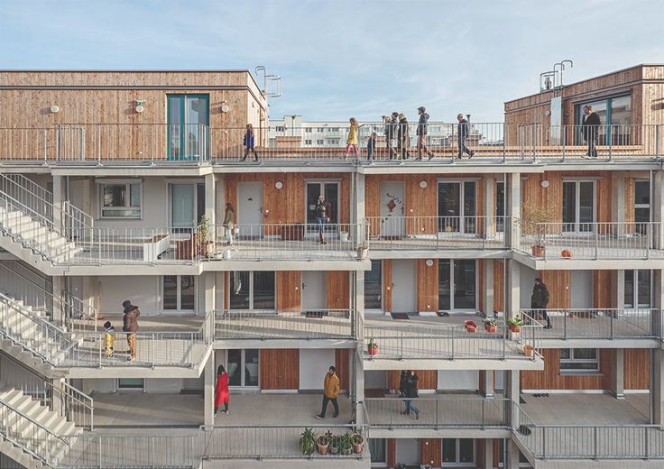 people are standing on the balconies of an apartment building with multiple floors and balconies