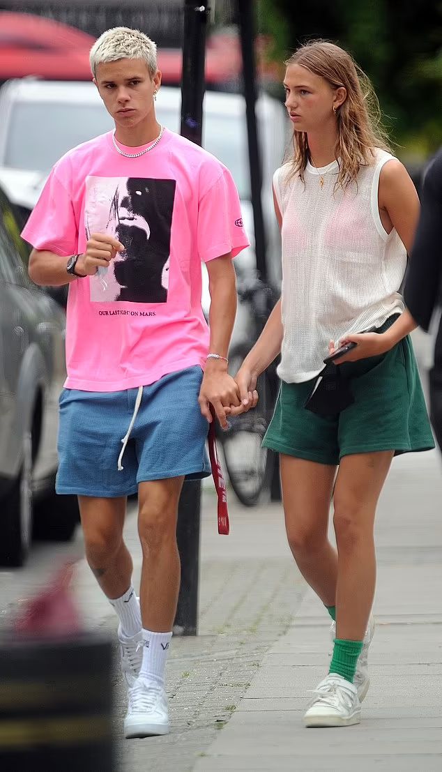 a man and woman walking down the street with their hands in each other's pockets