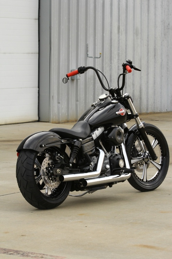 a black and silver motorcycle parked in front of a metal building with a red handlebar