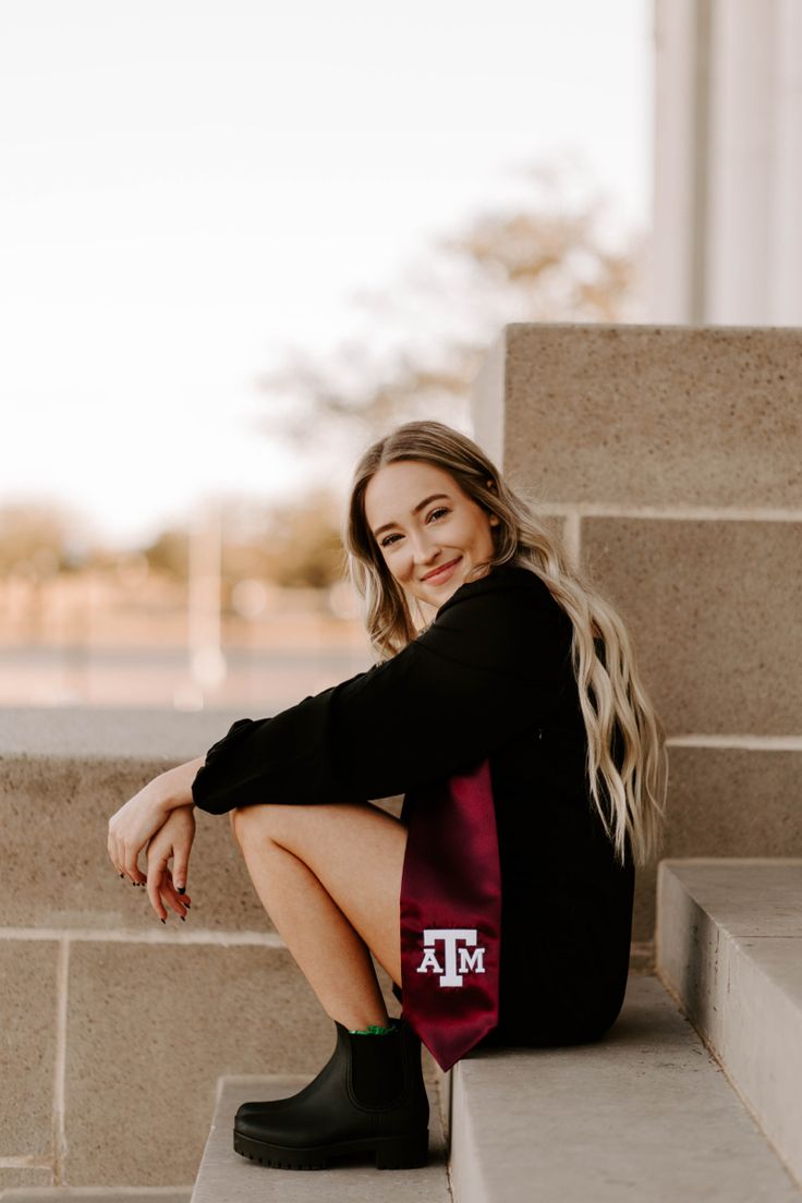 a woman sitting on the steps wearing black boots and a maroon texas state flag tote bag