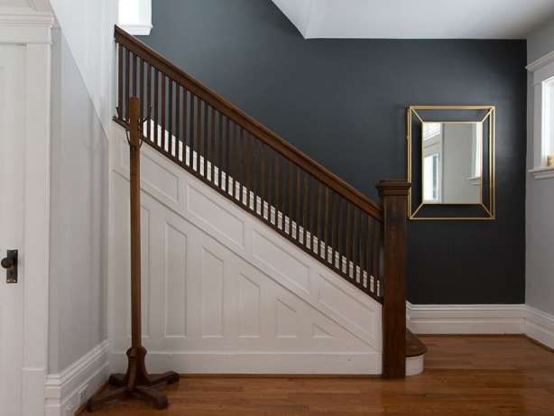 an empty room with a mirror on the wall next to a stair case and wooden floor