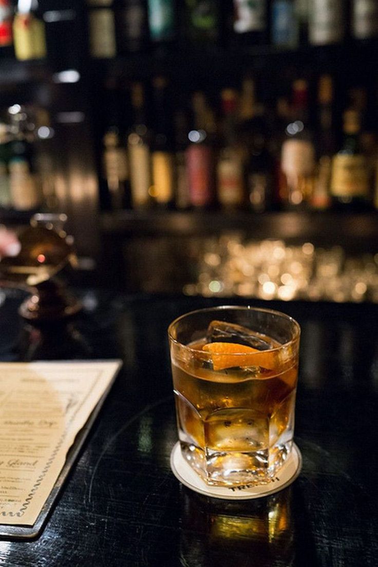 a glass filled with liquid sitting on top of a table next to a menu and pen