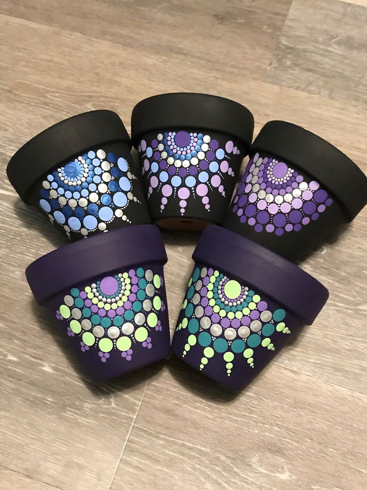 four purple and green polka dot patterned cups with black rims on wooden flooring