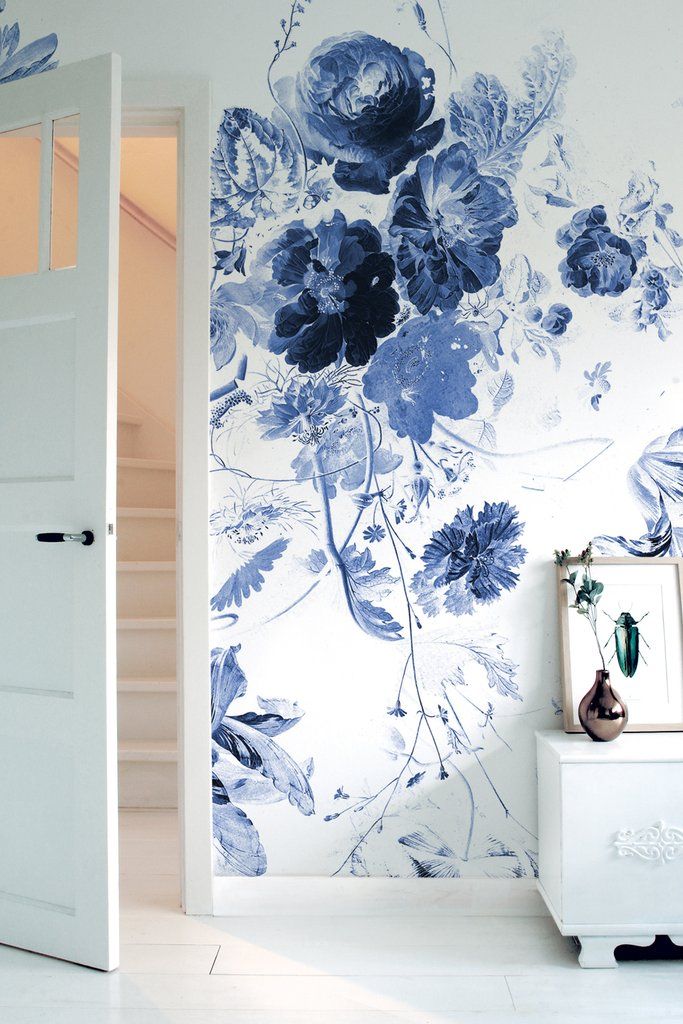 an open door leading into a room with blue flowers on the wall and white flooring