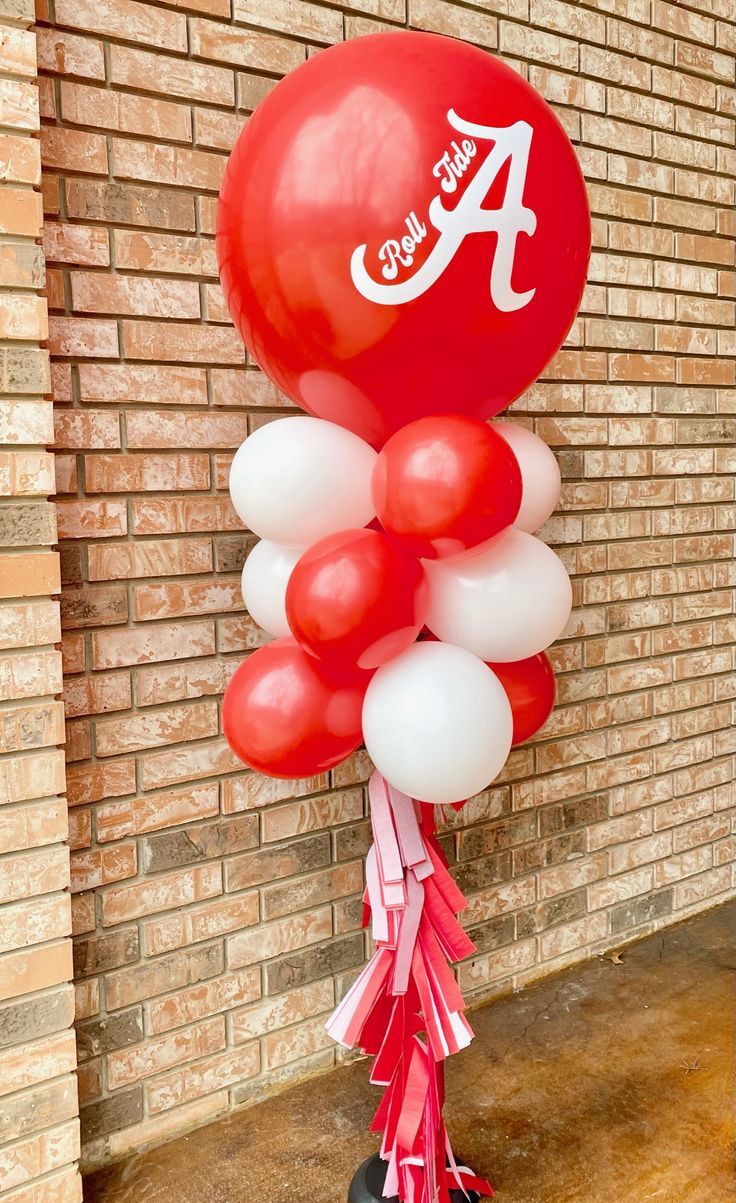 balloons and streamers in front of a brick wall with the letter a on it