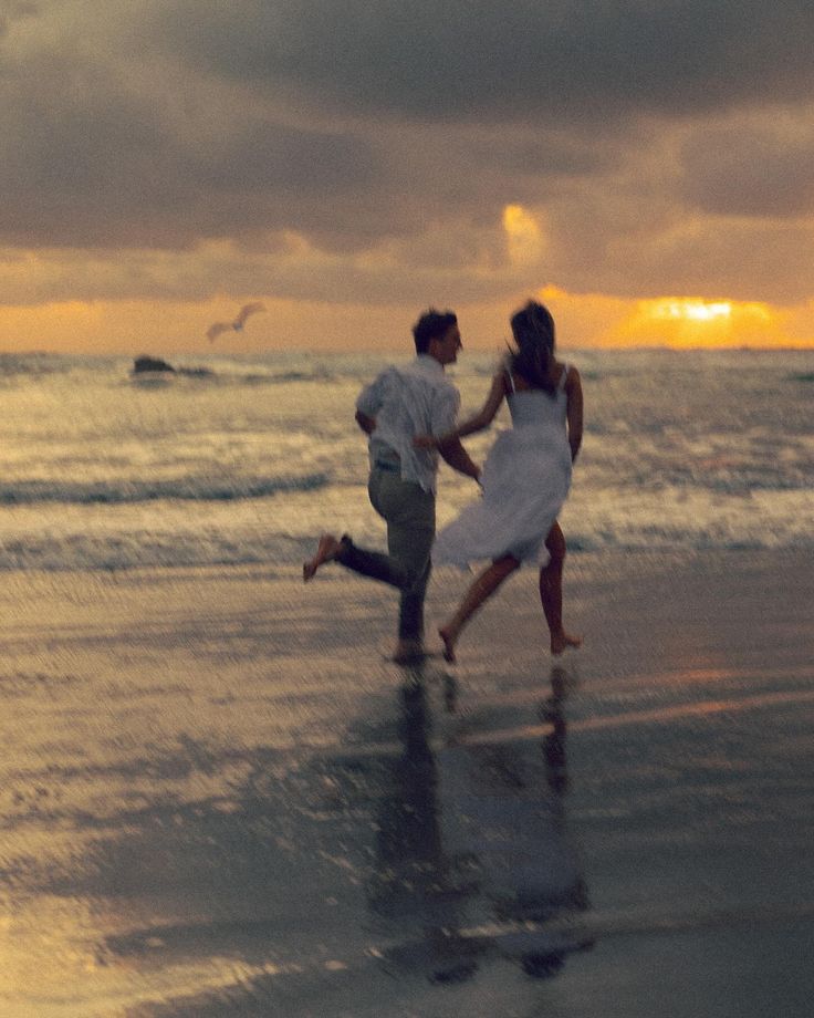 a couple running on the beach at sunset