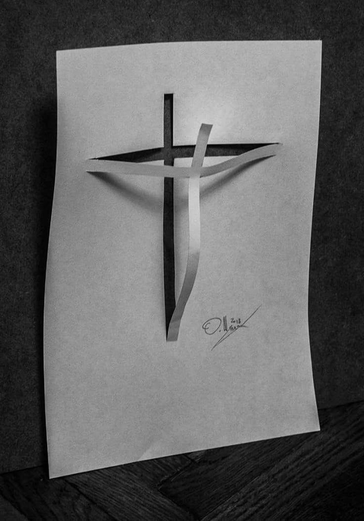 a cross on top of a piece of paper next to a pen and ink drawing