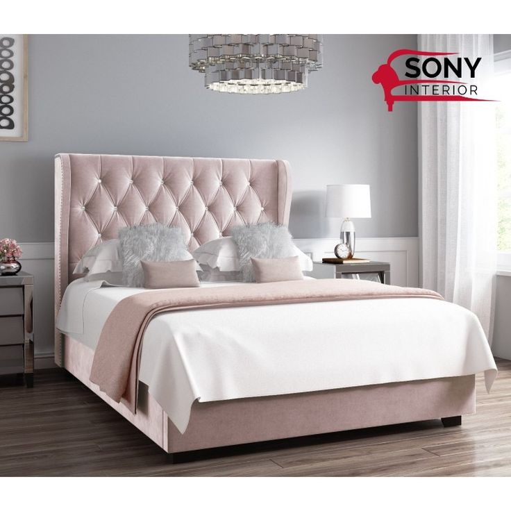 a bedroom with a pink bed and chandelier above the headboard is shown