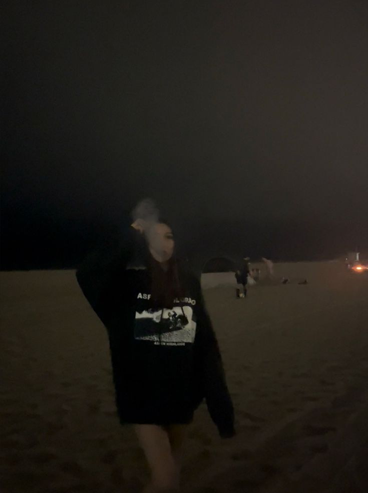 a man standing on top of a sandy beach at night