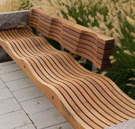 a wooden bench sitting on top of a stone walkway next to tall grass and plants