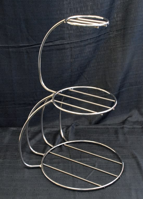 three tiered metal rack sitting on top of a black cloth