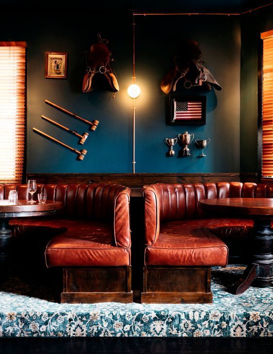 two brown leather couches sitting next to each other in front of a blue wall