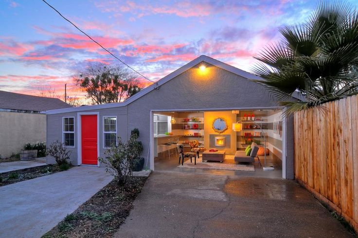 a house with a red door and palm tree in the front yard at sunset or dawn