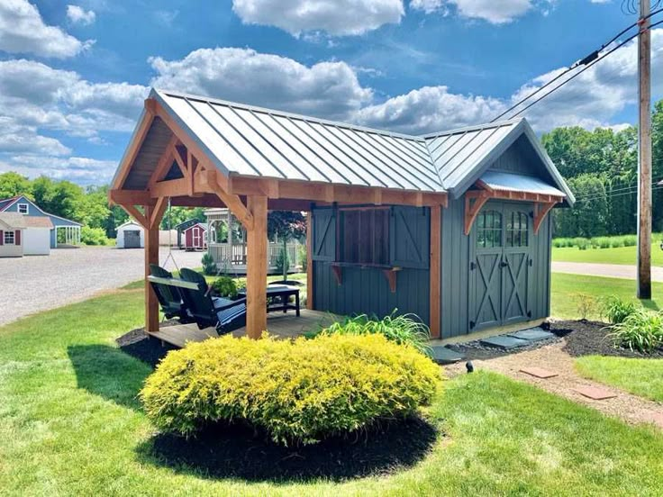 a small shed sitting in the middle of a lush green field