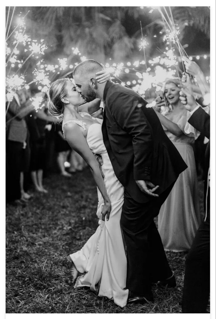 a bride and groom kissing while surrounded by sparklers