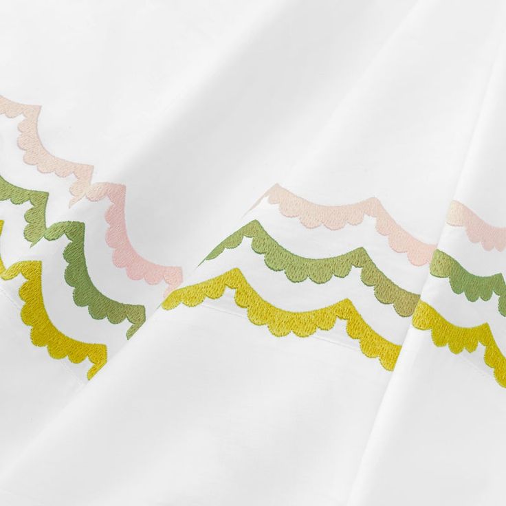 two pieces of white fabric with green, yellow and pink designs