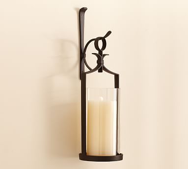 a candle that is sitting on a wall next to a glass holder with two candles in it