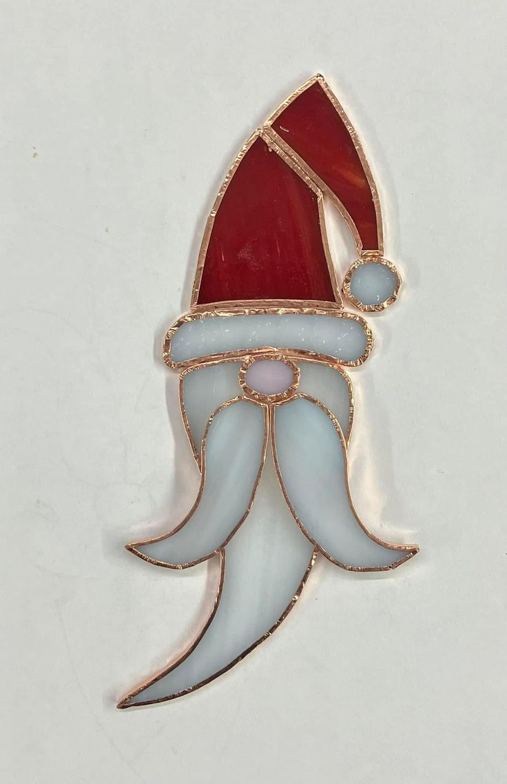 a red and white santa hat brooch sitting on top of a table