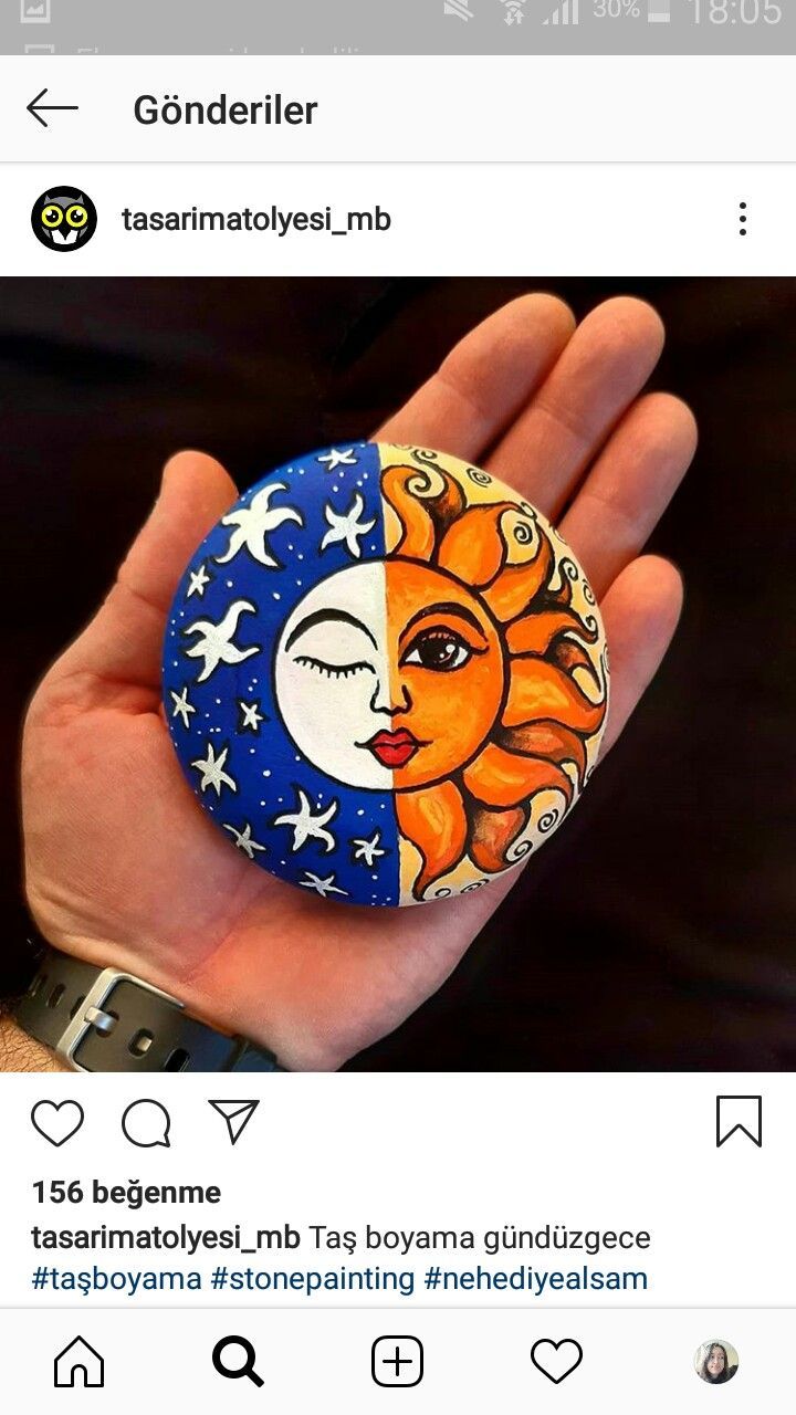 a hand holding a button with the sun and moon painted on it