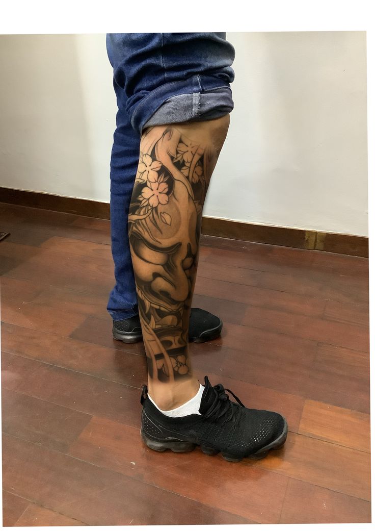 a person with tattoos on their legs standing in front of a man's leg