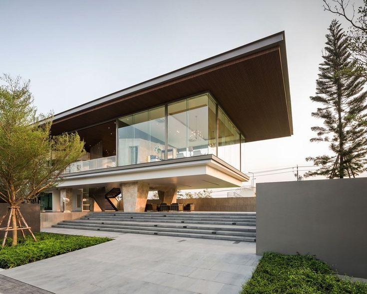 a modern house is shown from the outside with grass and bushes in front of it