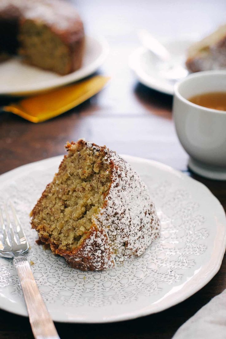 a piece of cake sitting on top of a white plate next to a cup of tea