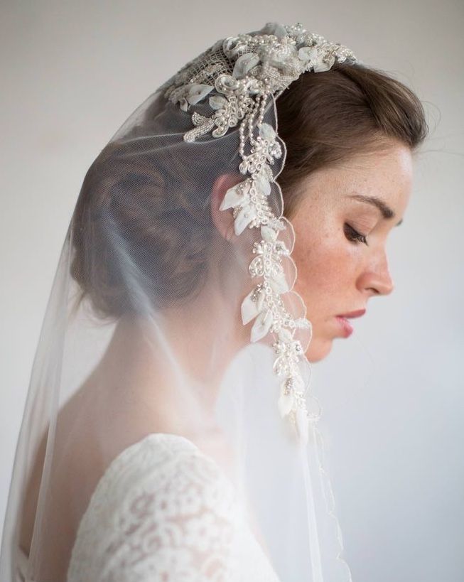 a woman wearing a veil with flowers on the head and hair comb in her hand