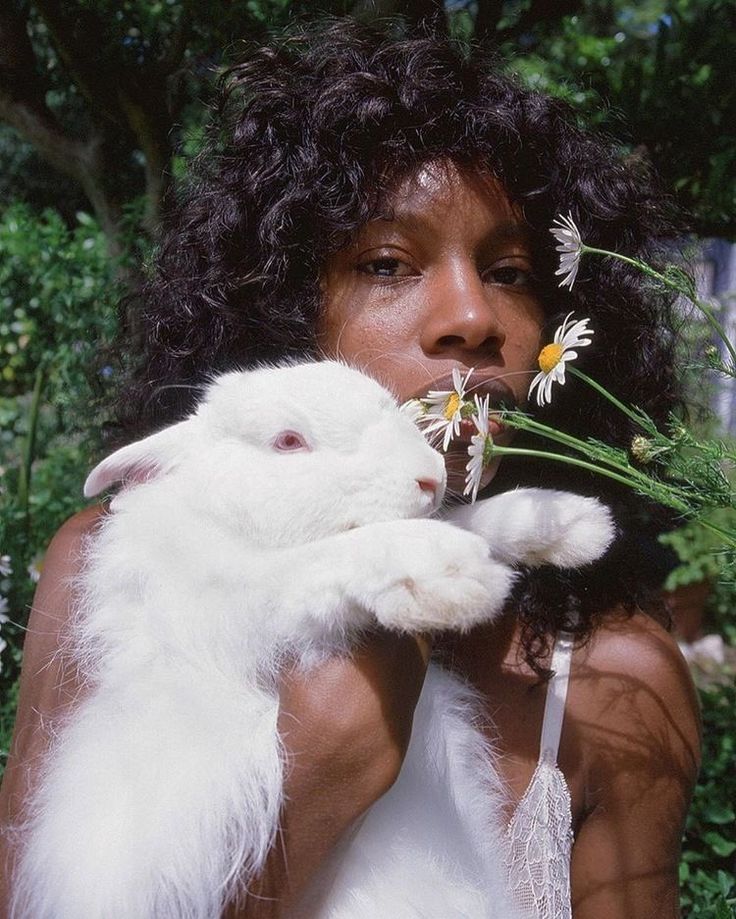 a woman holding a white bunny and flowers