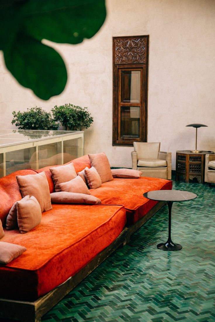 an orange couch sitting on top of a green floor next to a table and chair