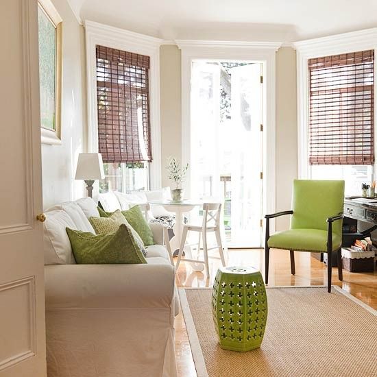 a living room filled with lots of furniture and windows covered in shades of light green